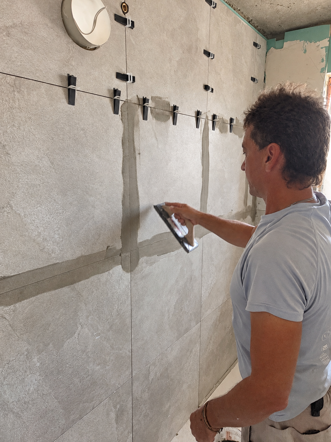 Constructor de Kamari trabajando en el alicatado de un baño